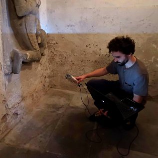 Operátor snímá skenerem historický náhrobek umístěný na zdi