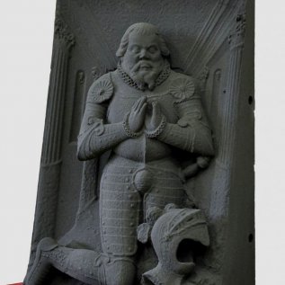 Replika náhrobku vyrobená 3D tiskem z písku vystavená na červeném stolku