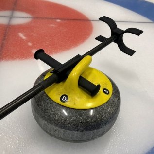 3D tištěná hůl pro curling položená na curlingovém kameni