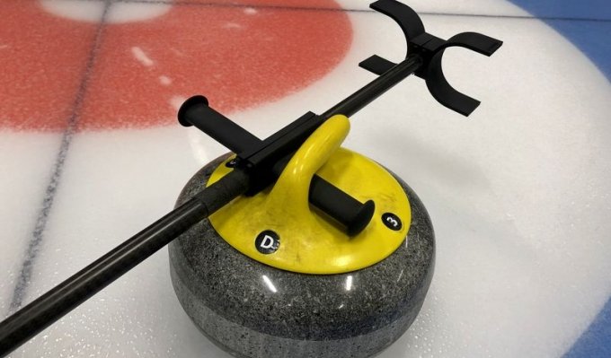 3D tištěná hůl pro curling položená na curlingovém kameni