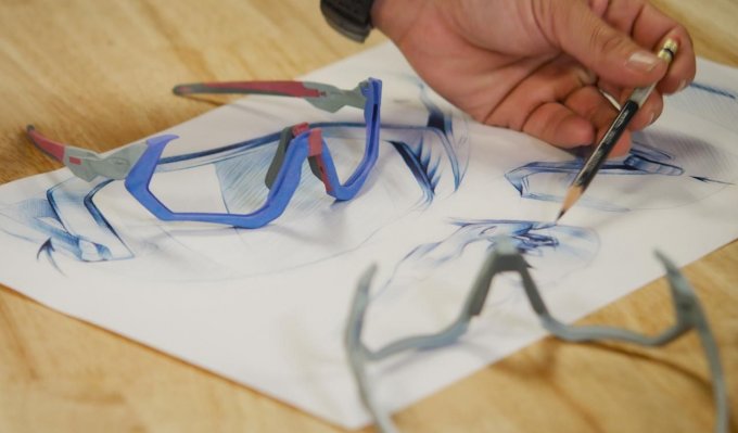 Barevné obroučky brýlí Oakley z 3D tiskárny leží na stole vedle technického výkresu
