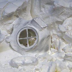 Hlavní díl respirátoru leží na nespotřebovaném prášku ve stavební jednotce 3D tiskárny