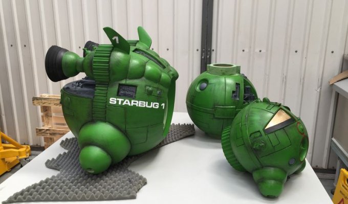 Díly vesmírné lodi z 3D tiskárny Voxeljet položené na bílém stole, nabarvené do syté zelené barvy