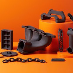 Různé díly vyrobené 3D tiskem na oranžovém pozadí
