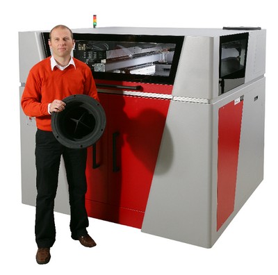 Operátor stojí před 3D tiskárnou Voxeljet a ruce drží výtisk
