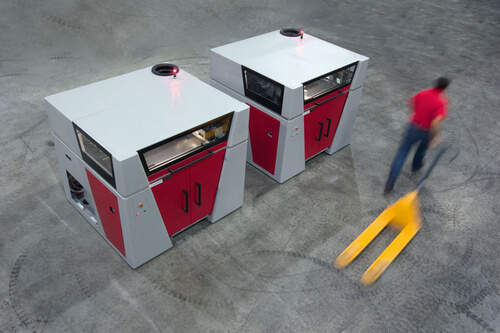 3D tiskárny Voxeljet ve velké hale, kolem projíždí operátor