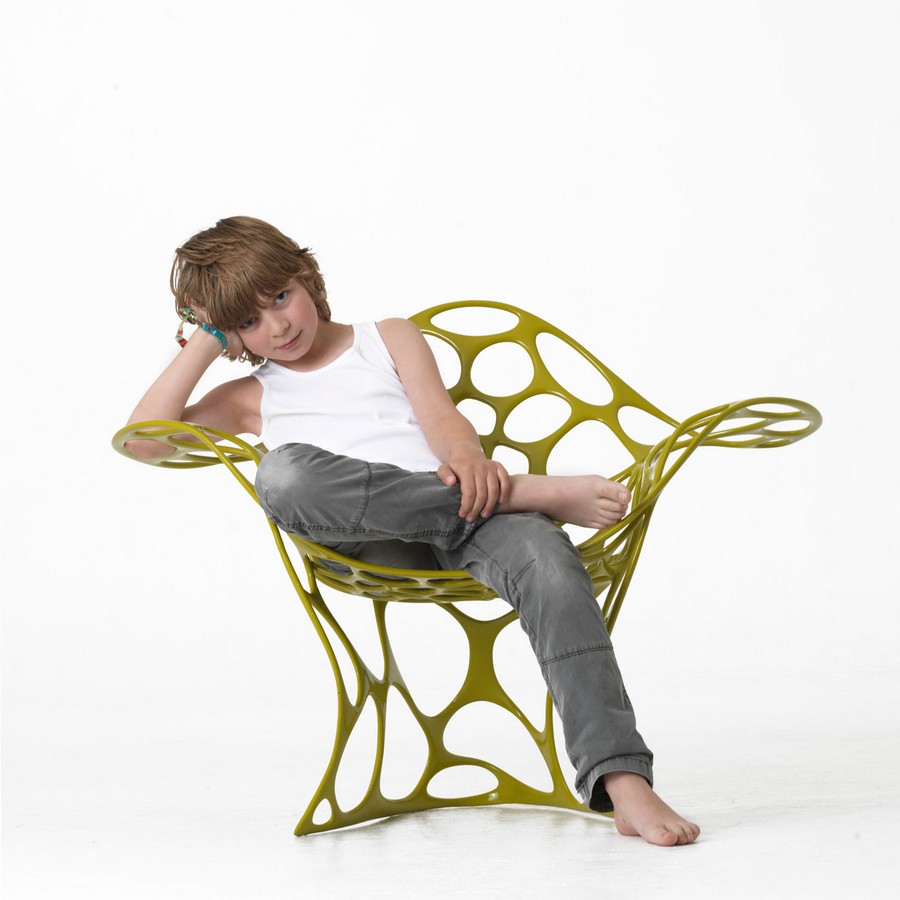 Dítě sedí v zeleném křesle organického designu a tvaru
